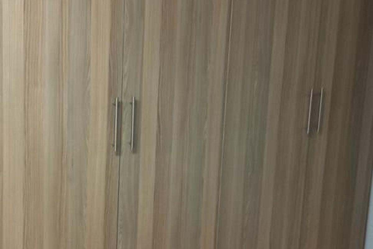 A utility space featuring full-height built-in cabinetry with wood-grain finish and tiled flooring.