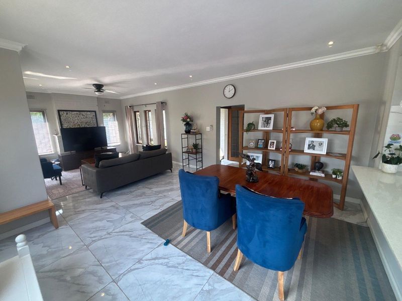 Spacious open-plan living and dining area featuring polished marble-look floor tiles, recessed downlighting, and crown molding throughout.