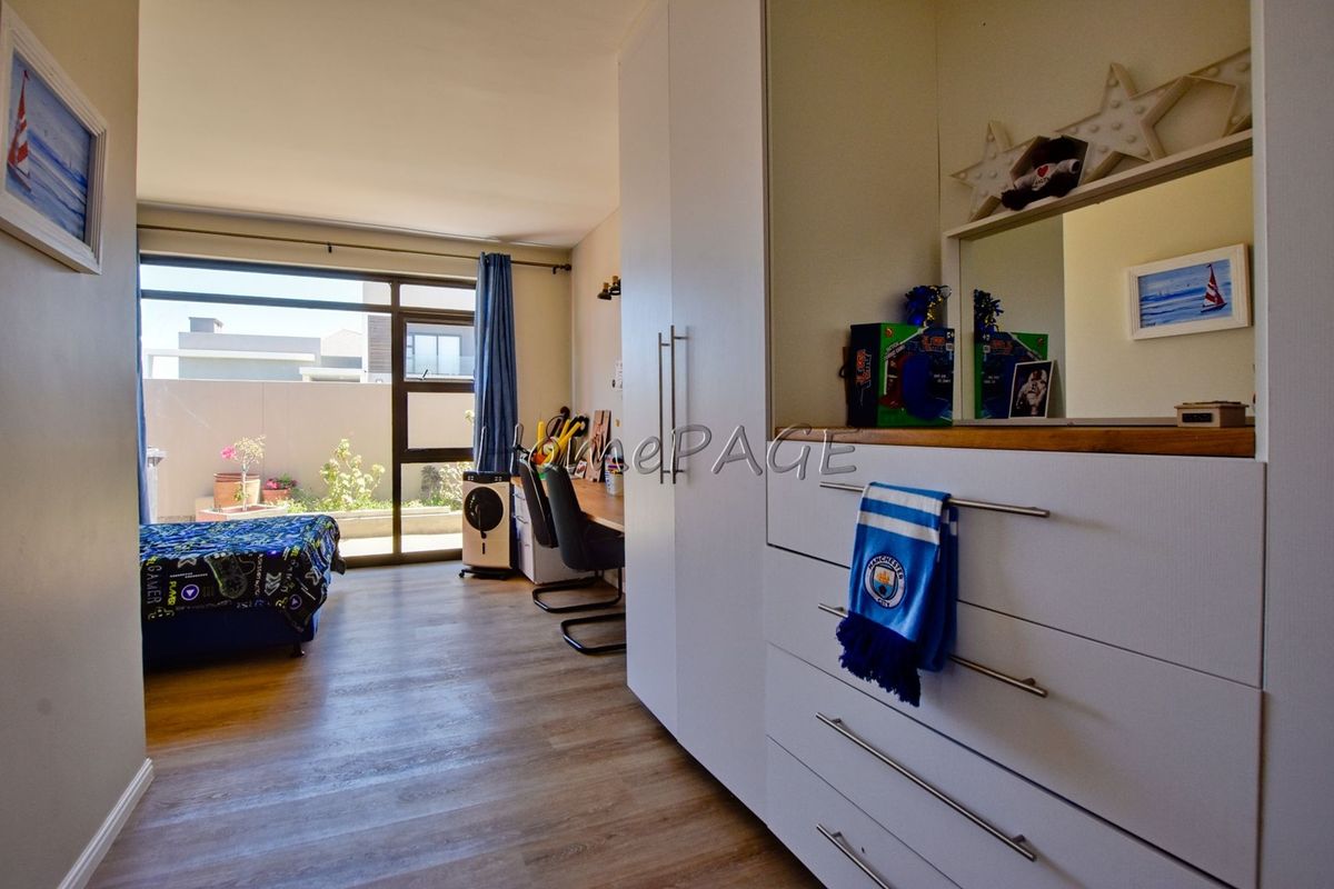 A well-lit bedroom featuring modern laminate flooring, a large built-in wardrobe, and a sliding glass door providing access to an outdoor area.
