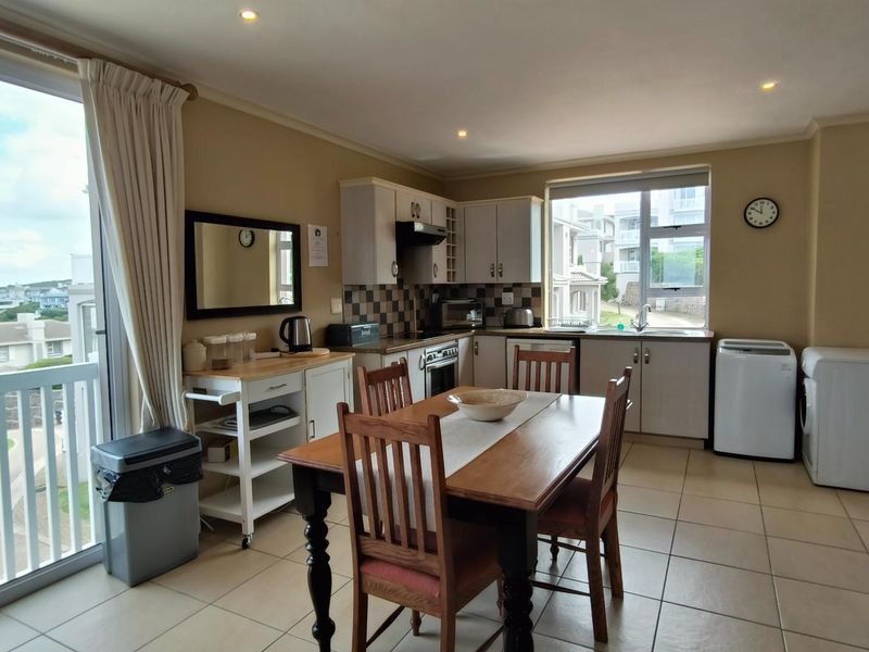 Open-plan kitchen and dining area featuring tiled flooring, built-in cabinetry, and a sliding glass door providing access to an outdoor balcony.
