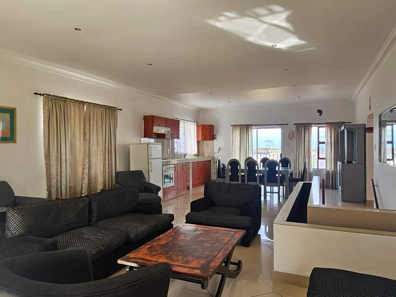 Spacious open-plan living and dining area featuring a functional kitchen with built-in cabinetry, tiled floors, and direct access to a balcony with views.