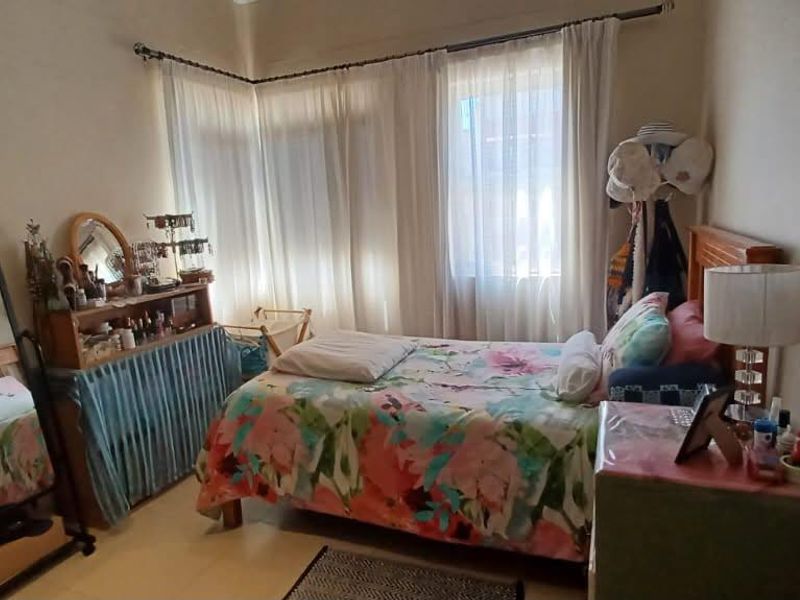 A standard bedroom featuring tiled flooring and large windows with curtain rods, offering a functional space with natural light.