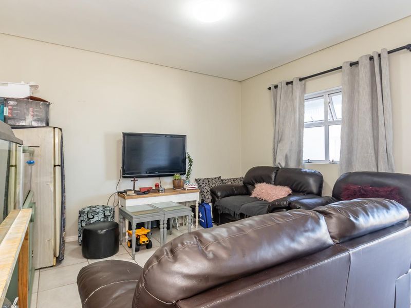 A functional living room featuring tiled flooring and a window with a curtain rod, providing a neutral base for interior updates.