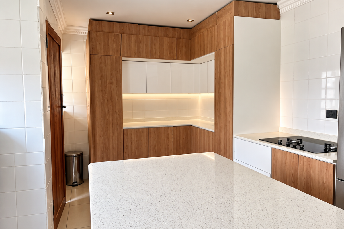 Modern kitchen featuring sleek wood-tone and white cabinetry, a spacious stone-topped island, integrated hob, and clean tiled splashbacks with ambient under-cabinet lighting.