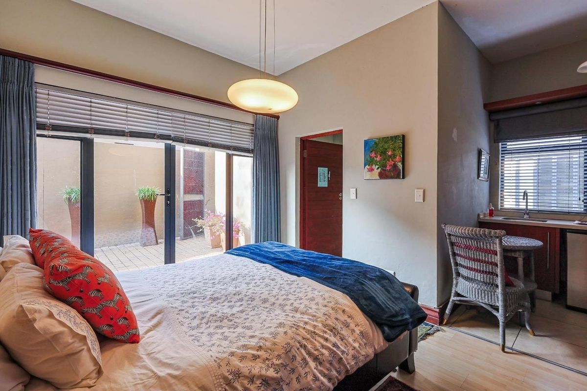 A bedroom featuring sliding glass doors leading to a private patio, with an integrated kitchenette area including a sink and cabinetry.