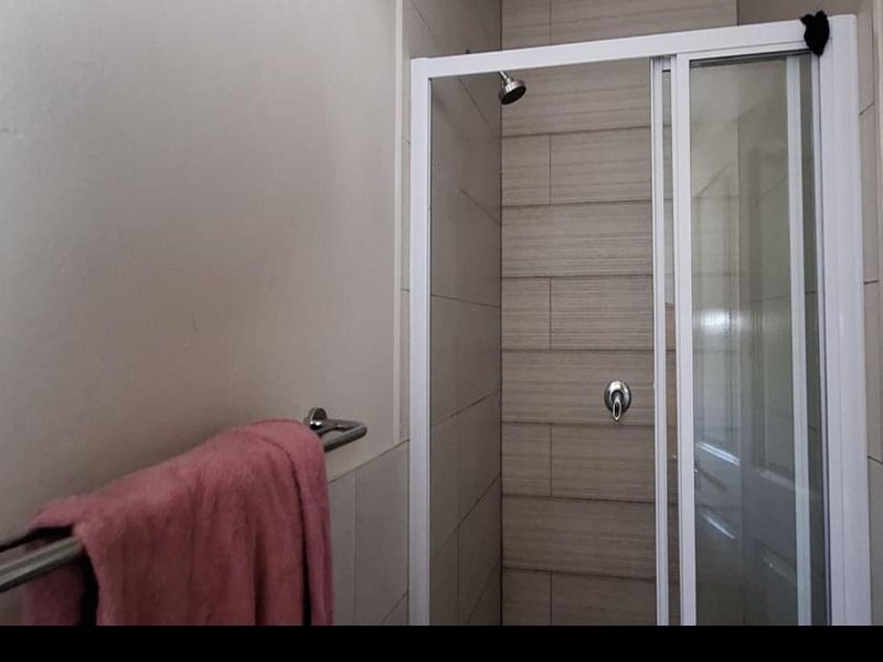 A clean bathroom featuring a tiled shower enclosure with a sliding glass door and a wall-mounted towel rail.