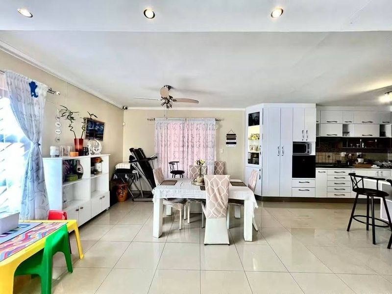 Spacious open-plan living, dining, and kitchen area featuring tiled flooring, recessed lighting, and functional built-in cabinetry with integrated appliances.