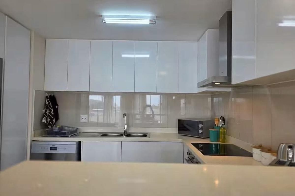 Modern kitchen featuring white gloss cabinetry, stone countertops, a stainless steel extractor fan, and a sleek electric hob with a tiled splashback.