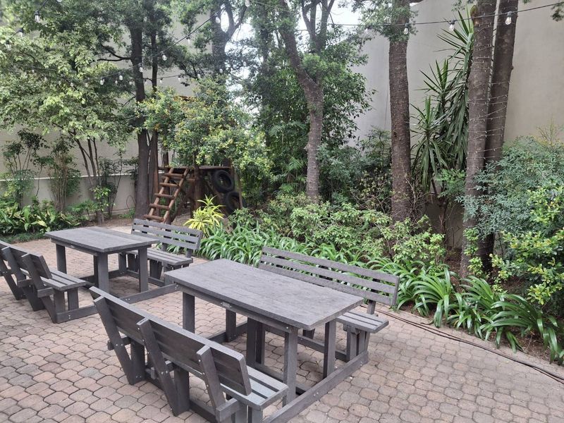 A tranquil garden area featuring paved patio space, mature trees, and established landscaping, perfect for outdoor relaxation.