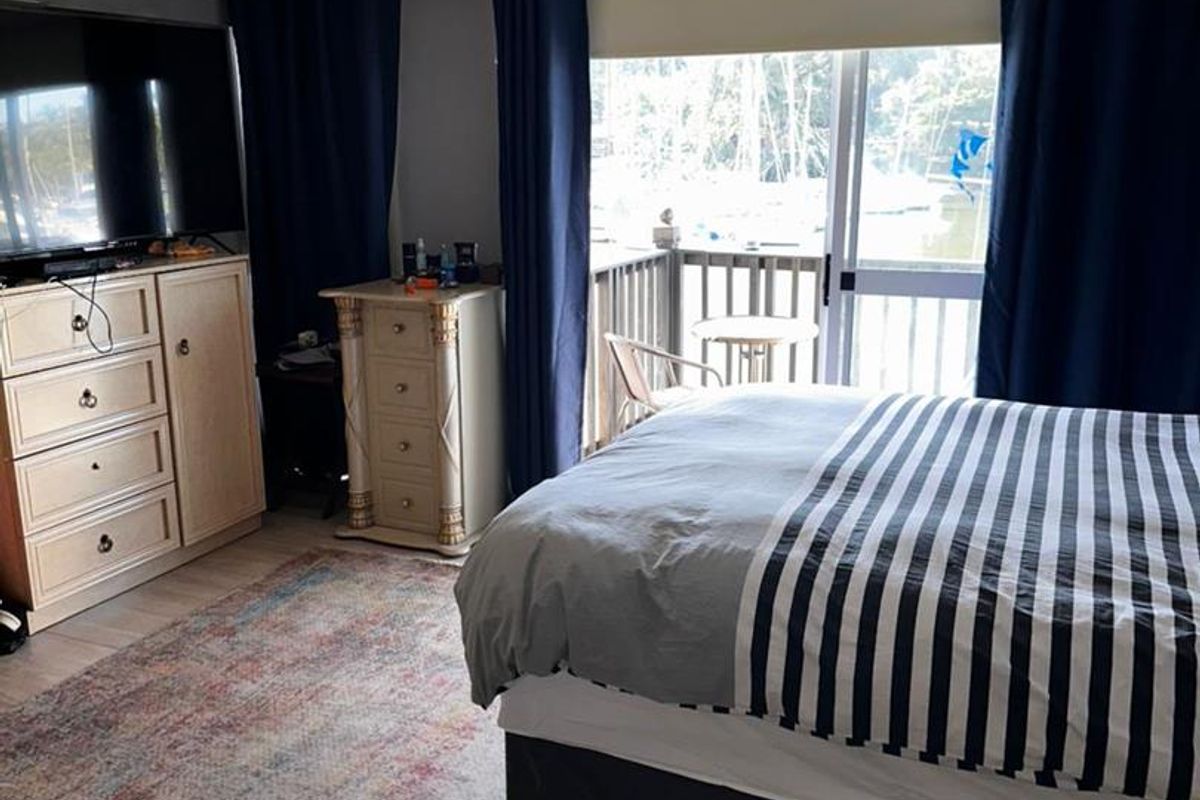 A bedroom featuring tiled flooring, a ceiling-mounted light fixture, and sliding glass doors that open onto a private balcony.
