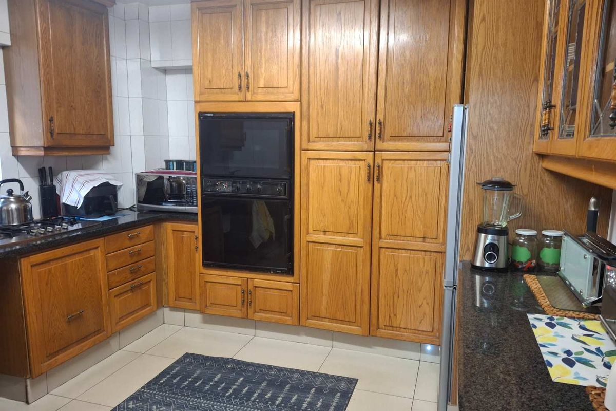 A functional kitchen featuring traditional oak cabinetry, dark granite countertops, and a built-in double oven, offering ample storage and workspace.
