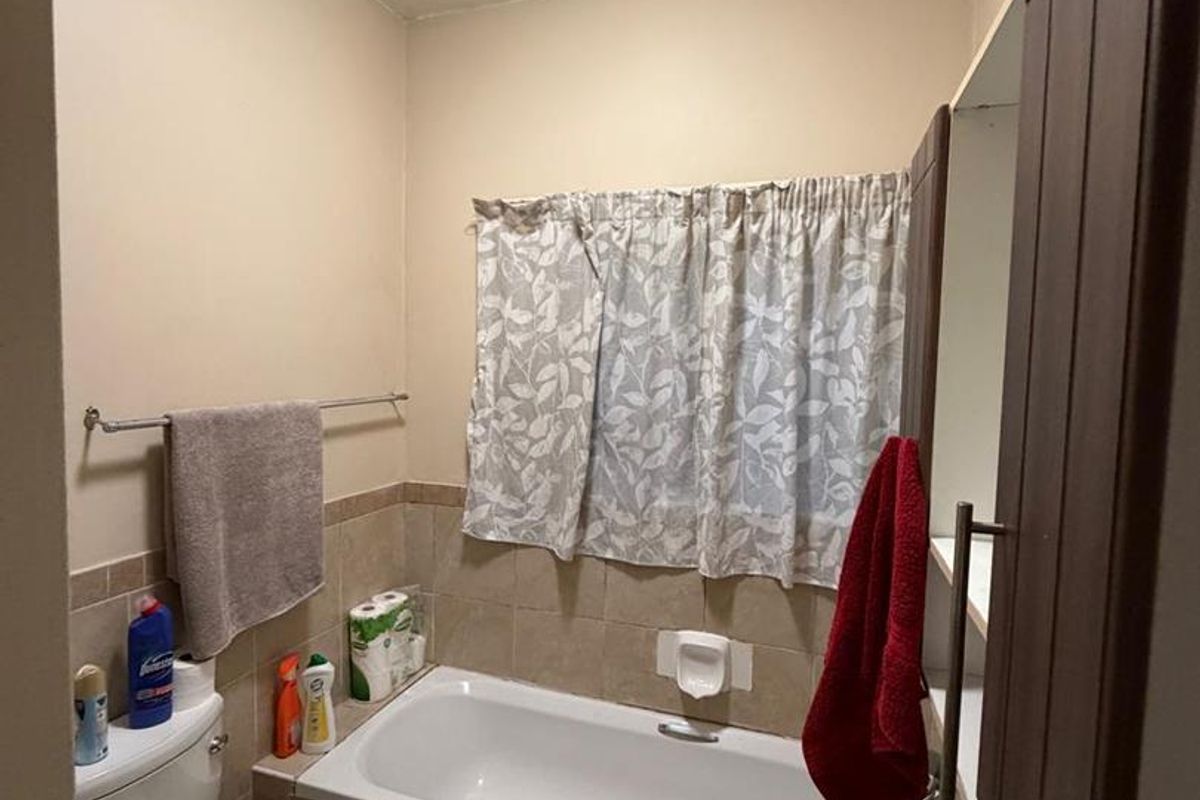 A compact bathroom featuring a built-in bathtub with tiled surround, a standard toilet, and a wall-mounted basin.