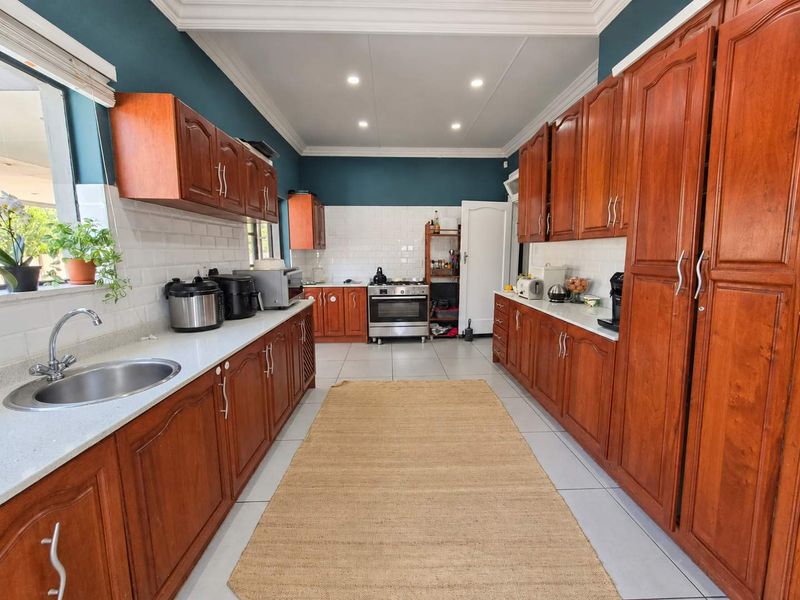 Spacious kitchen featuring warm wooden cabinetry, white subway tile backsplash, stone countertops, and a freestanding oven, offering a functional and classic layout.