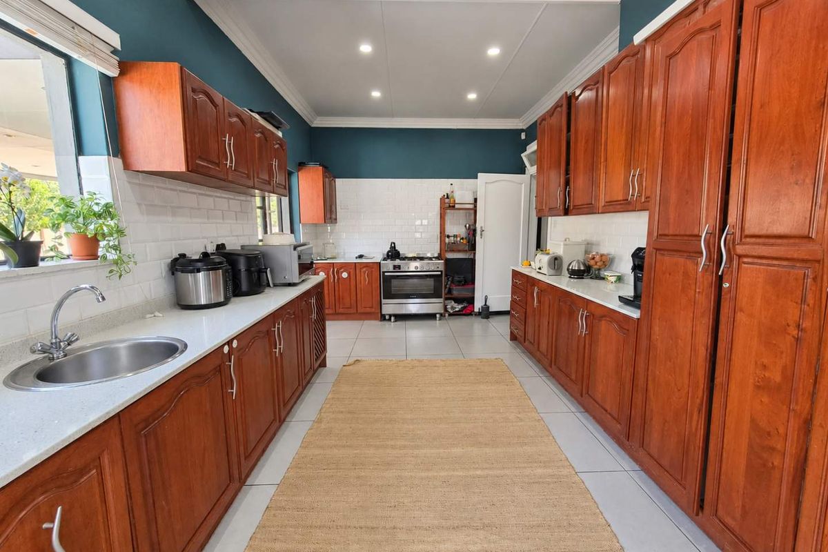 Spacious kitchen featuring warm wooden cabinetry, white subway tile backsplash, stone countertops, and a freestanding oven, offering a functional and classic layout.