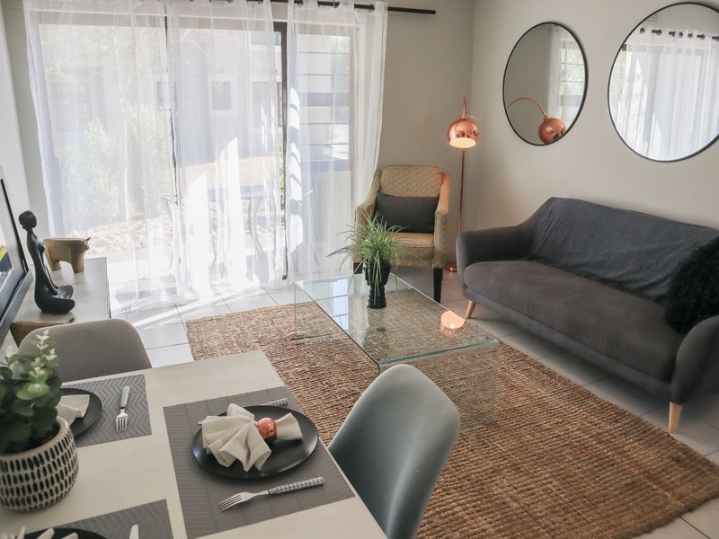 Bright open-plan living and dining area featuring tiled flooring and large sliding glass doors providing access to the outdoor space.