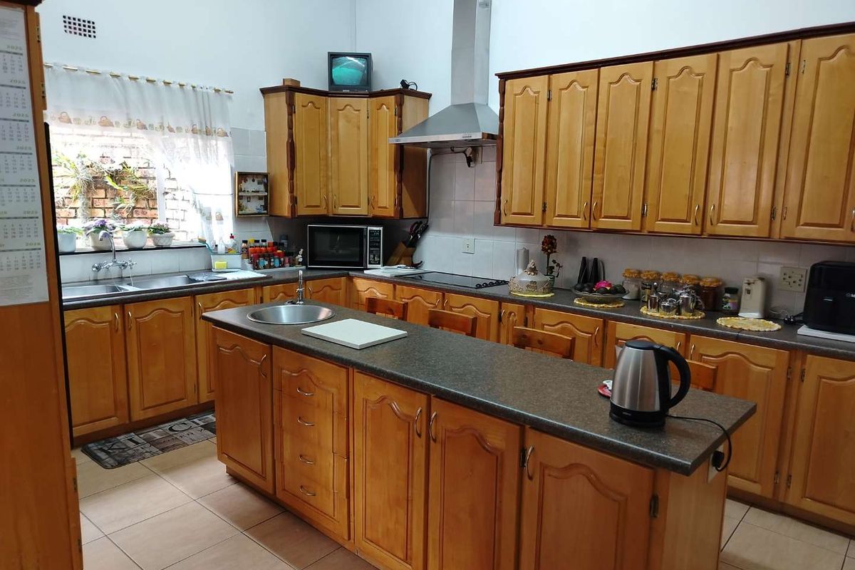 A functional kitchen featuring traditional wooden cabinetry, a central island with a secondary sink, laminate countertops, and tiled flooring.