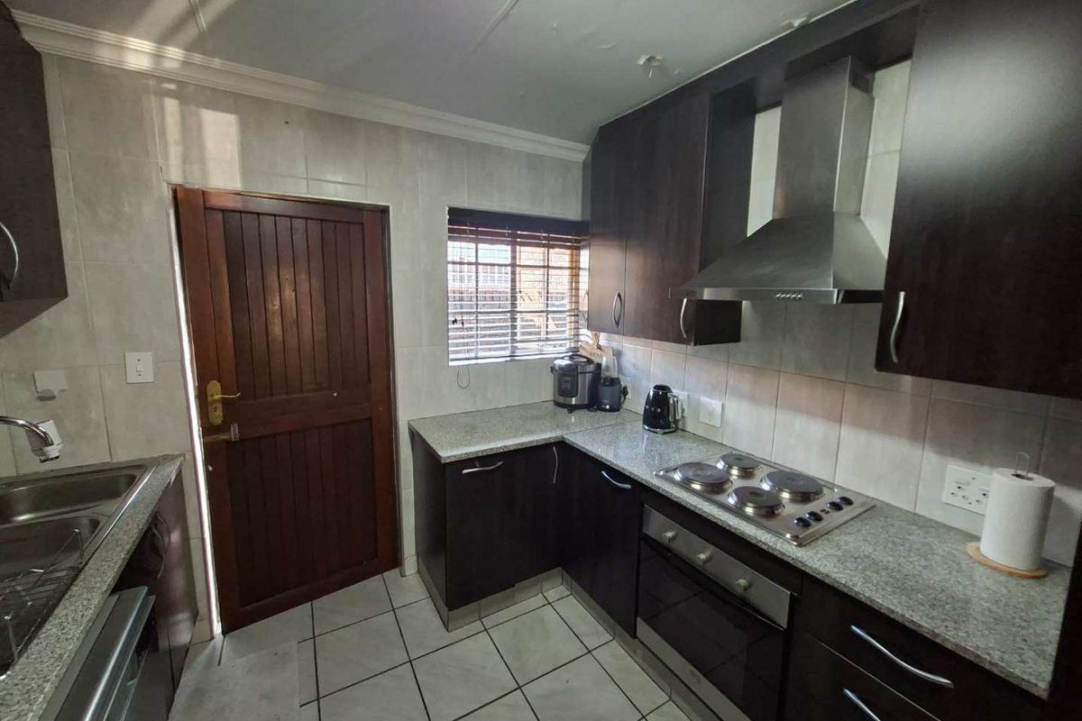Compact kitchen featuring dark cabinetry, granite countertops, built-in oven, and hob, with visible ceiling maintenance required.