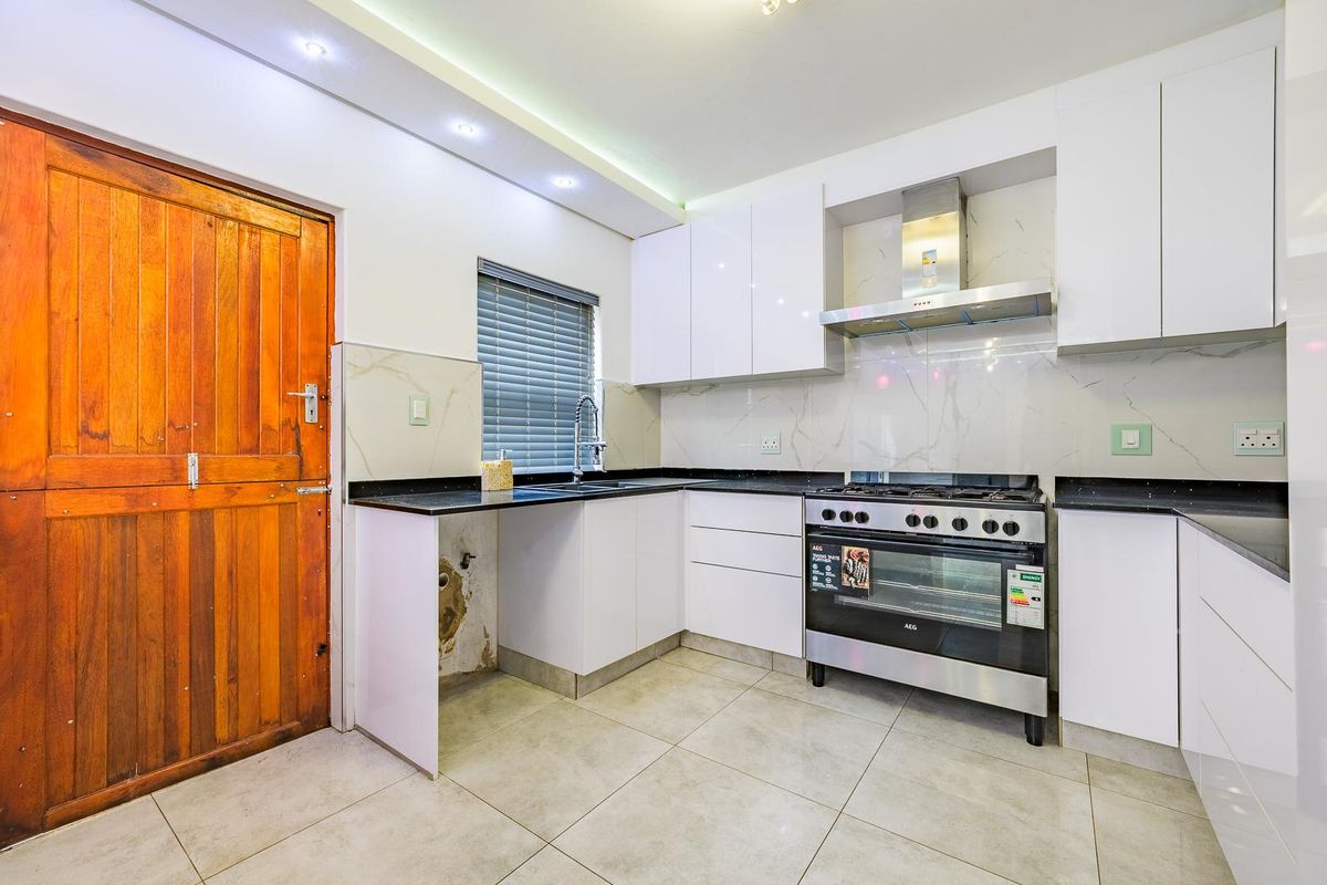 Modern kitchen featuring white cabinetry, stone countertops, stainless steel oven, gas hob, and tiled flooring. Requires minor repairs to cabinetry under the sink.
