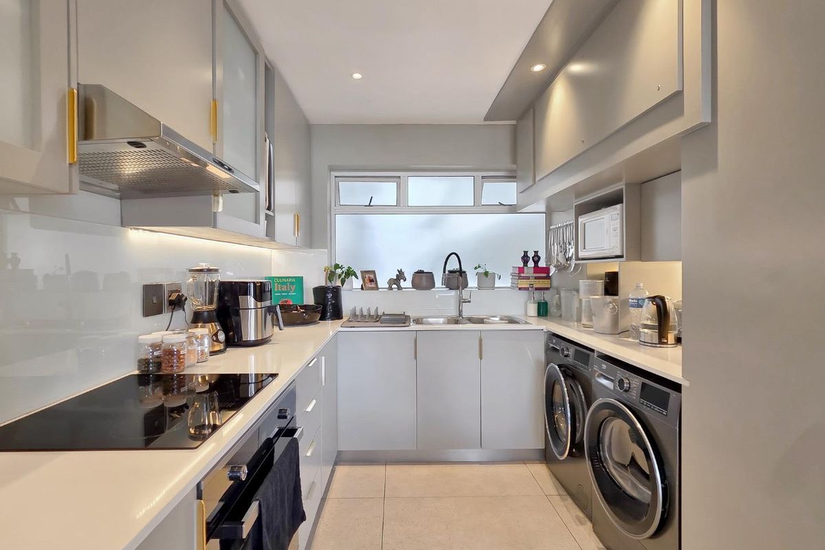 Modern galley-style kitchen featuring sleek grey cabinetry, quartz countertops, integrated appliances, and high-quality finishes with efficient use of space.