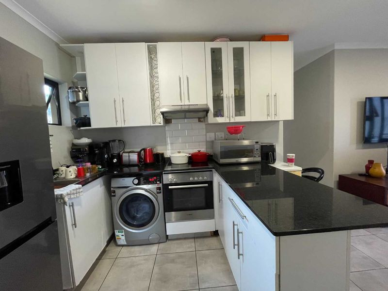 A functional kitchen featuring white cabinetry, black granite countertops, subway tile backsplash, and integrated oven with extractor fan.