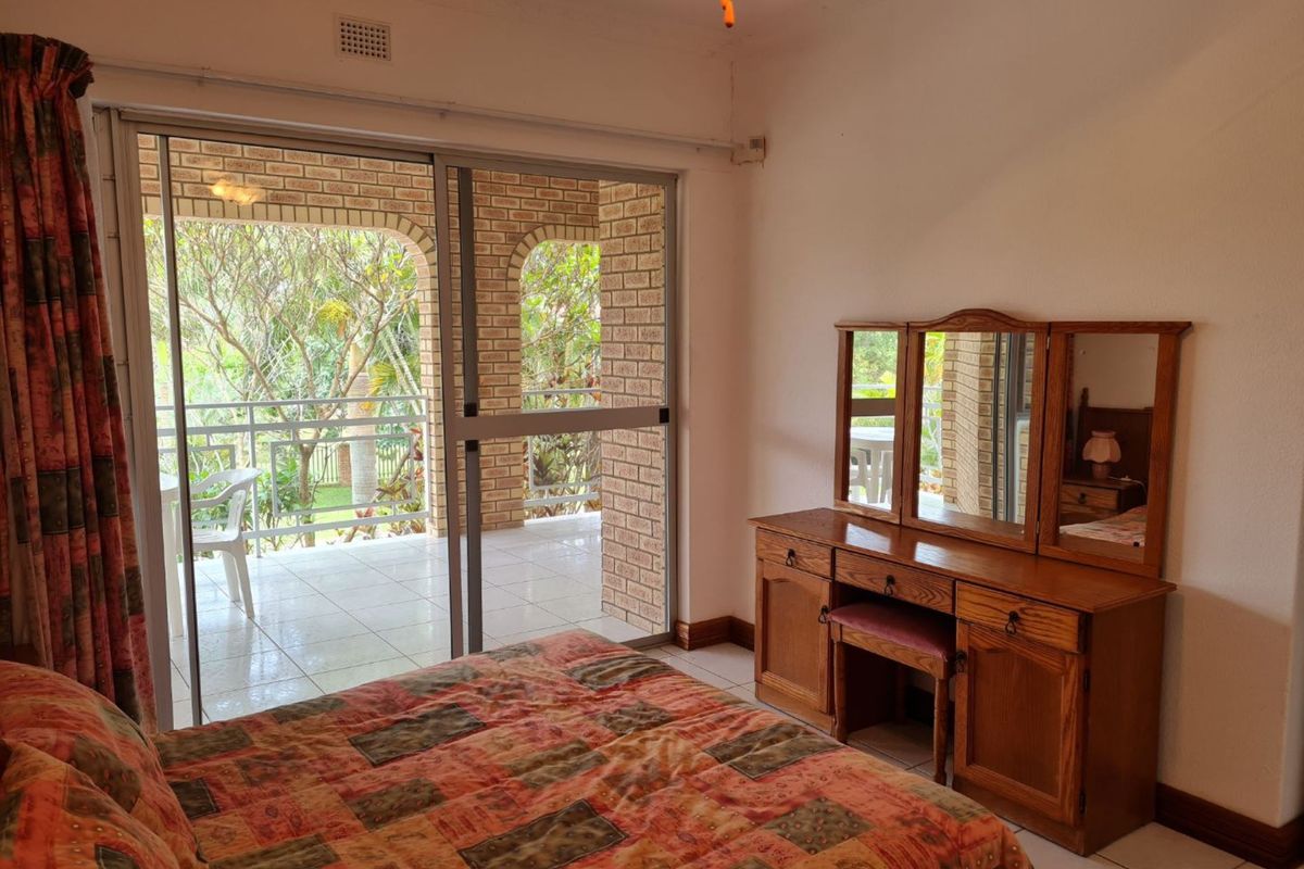 A bedroom featuring tiled flooring, ceiling fan, and large sliding glass doors providing direct access to a covered patio area.