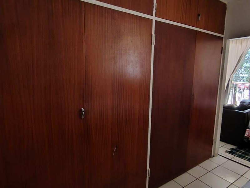 Bedroom featuring extensive built-in wooden cupboards and tiled flooring, offering ample storage space with a dated aesthetic.