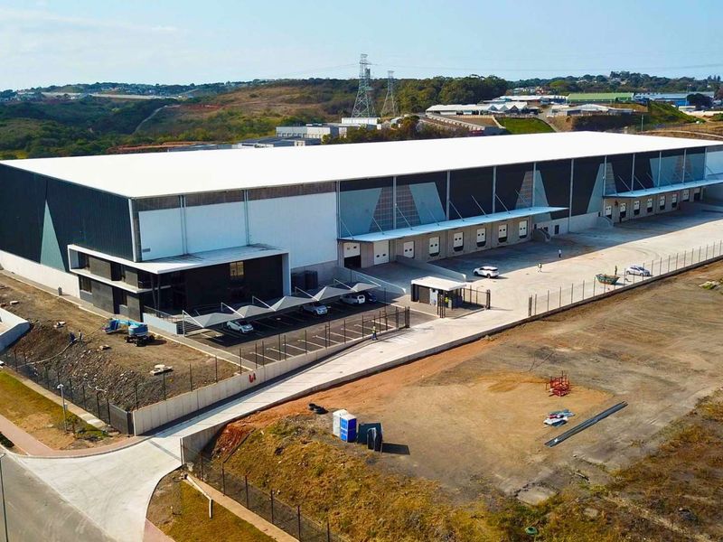 Aerial view of a modern industrial warehouse facility featuring multiple loading docks, secure perimeter fencing, and dedicated covered parking areas.