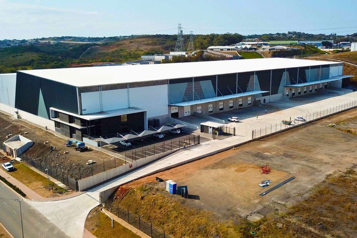 Aerial view of a modern industrial warehouse facility featuring multiple loading docks, secure perimeter fencing, and dedicated covered parking areas.