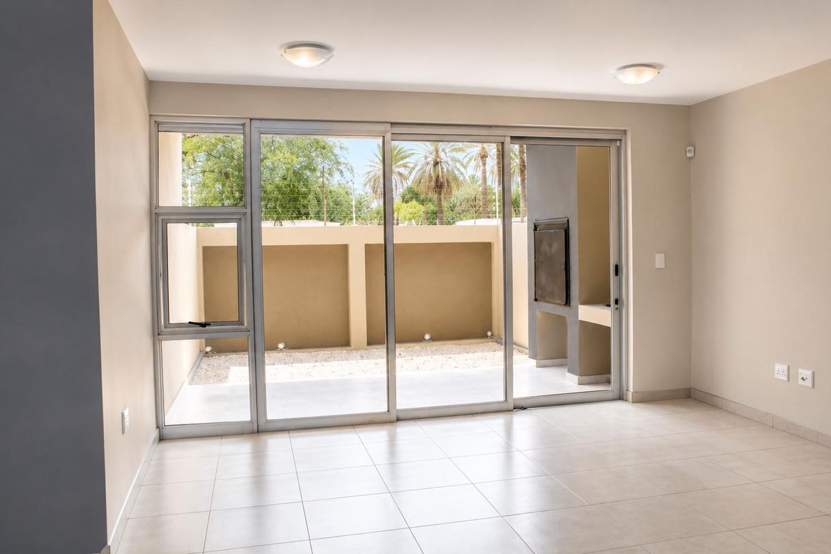 Bright living area featuring large sliding glass doors that open onto a private paved patio with a built-in braai.