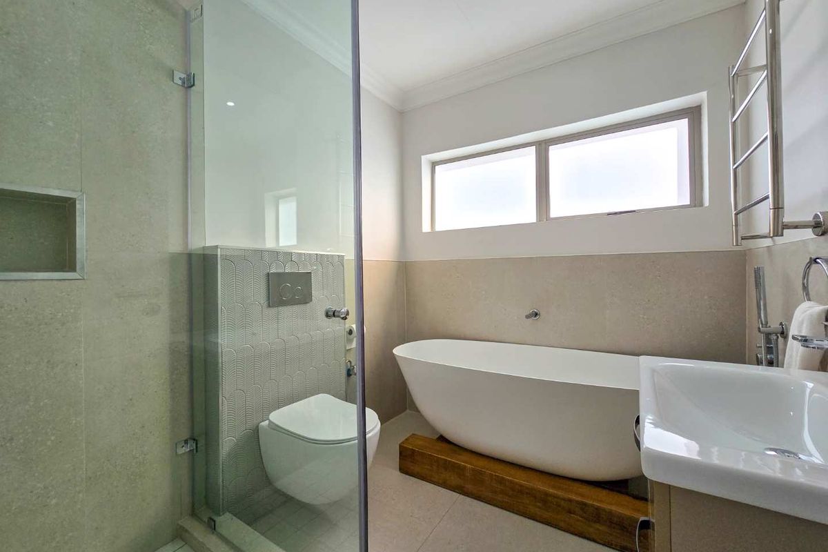 Modern bathroom featuring a freestanding bathtub, a glass-enclosed walk-in shower, a wall-mounted toilet, and a heated towel rail.