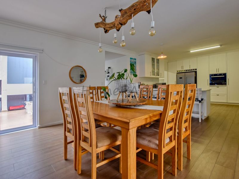 Spacious open-plan living and dining area featuring modern kitchen cabinetry, integrated appliances, and seamless access to the outdoor patio through sliding glass doors.