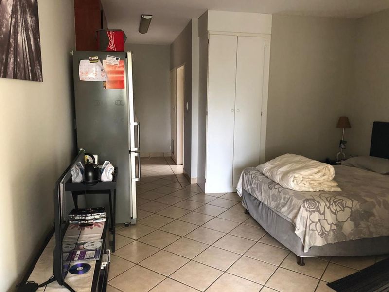 A bedroom featuring tiled flooring and a built-in cupboard, providing functional storage space within the apartment.