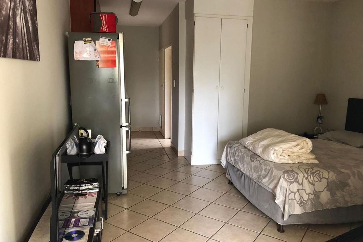 A bedroom featuring tiled flooring and a built-in cupboard, providing functional storage space within the apartment.
