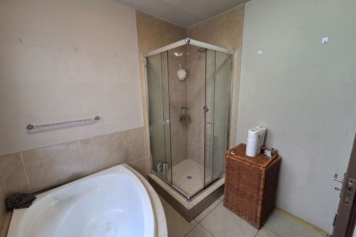 Bathroom featuring a corner bathtub, a separate glass-enclosed shower stall, and tiled flooring.