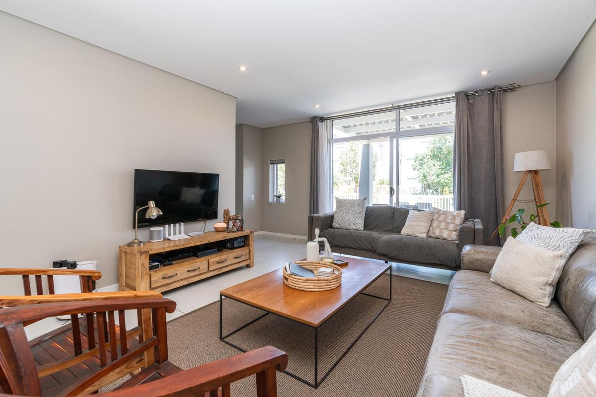 A bright and spacious living room featuring neutral walls, tiled flooring, and large sliding glass doors that provide access to the outdoor area.