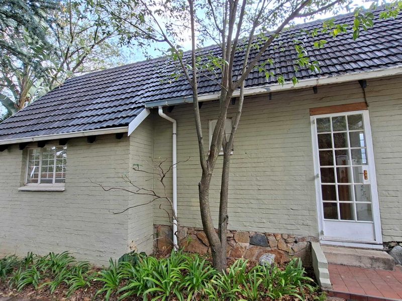 Rear exterior view of the cottage featuring a tiled roof, painted brick walls with stone base detailing, and a classic french door entrance.