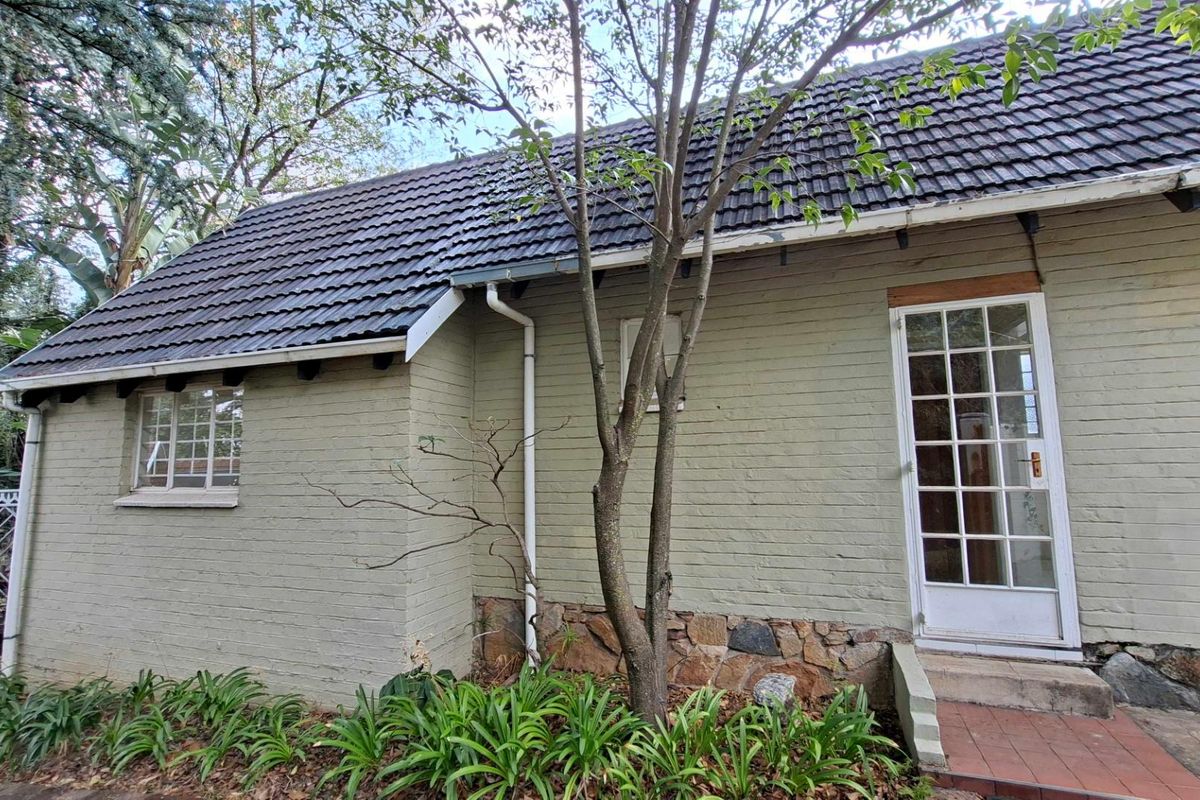 Rear exterior view of the cottage featuring a tiled roof, painted brick walls with stone base detailing, and a classic french door entrance.