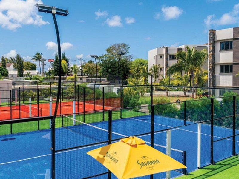 Well-maintained outdoor sports facility featuring multiple padel courts with professional synthetic turf surfaces, perimeter fencing, and integrated floodlighting.