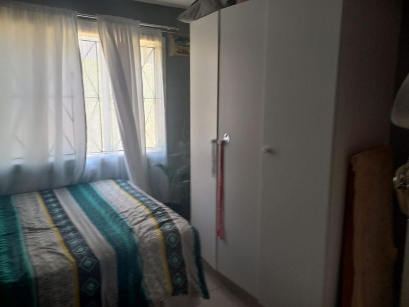 A bedroom featuring a built-in wardrobe and a window with security bars, providing natural light and functional storage space.