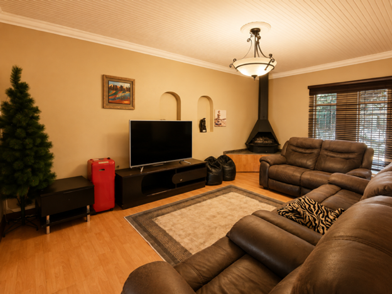 A comfortable living room featuring a corner fireplace, recessed wall niches, and beadboard ceiling detail, providing a cozy atmosphere.