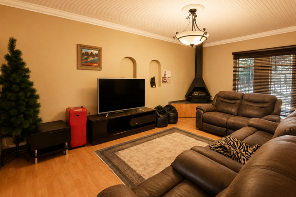 A comfortable living room featuring a corner fireplace, recessed wall niches, and beadboard ceiling detail, providing a cozy atmosphere.