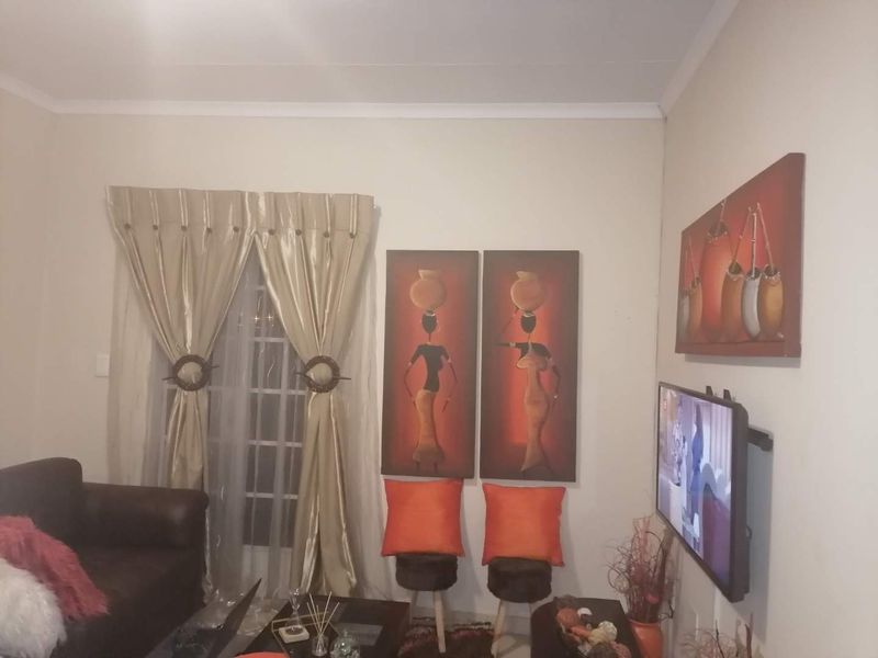 A living room area featuring a window with curtains and decorative wall finishes.