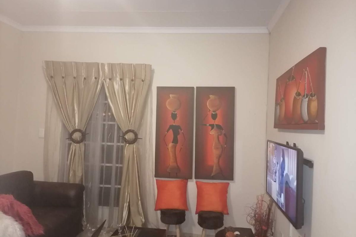 A living room area featuring a window with curtains and decorative wall finishes.