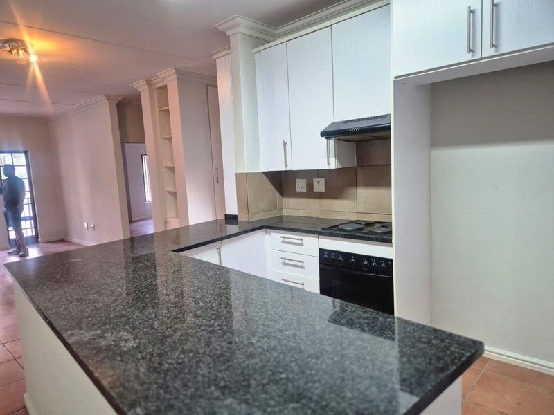 A clean, functional kitchen featuring granite countertops, built-in cabinetry, and integrated cooking appliances, opening into the main living area.