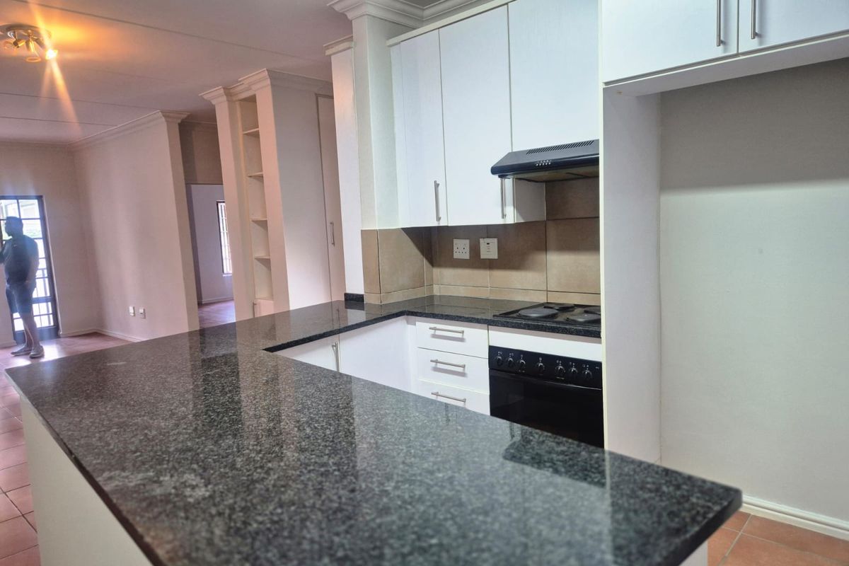 A clean, functional kitchen featuring granite countertops, built-in cabinetry, and integrated cooking appliances, opening into the main living area.
