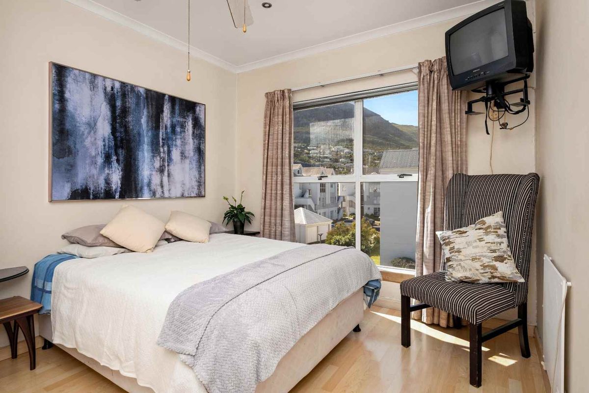 A bedroom featuring laminate flooring, coving, and a ceiling fan, with a window offering natural light and views.