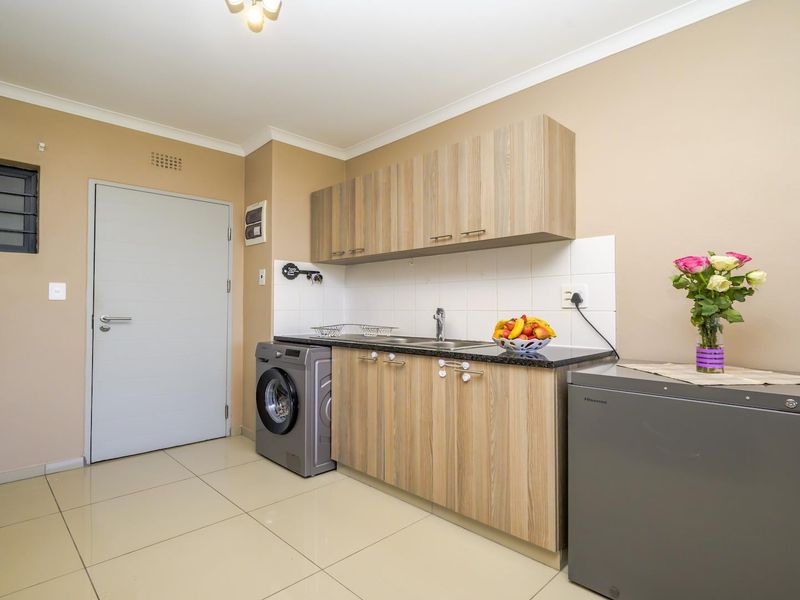 A functional kitchen featuring laminate cabinetry, granite countertops, tiled flooring, and a tiled splashback, providing a clean and practical workspace.