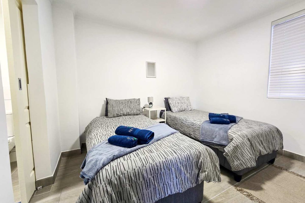 A bright bedroom featuring tiled flooring, a window with fitted blinds, and a neutral color palette.