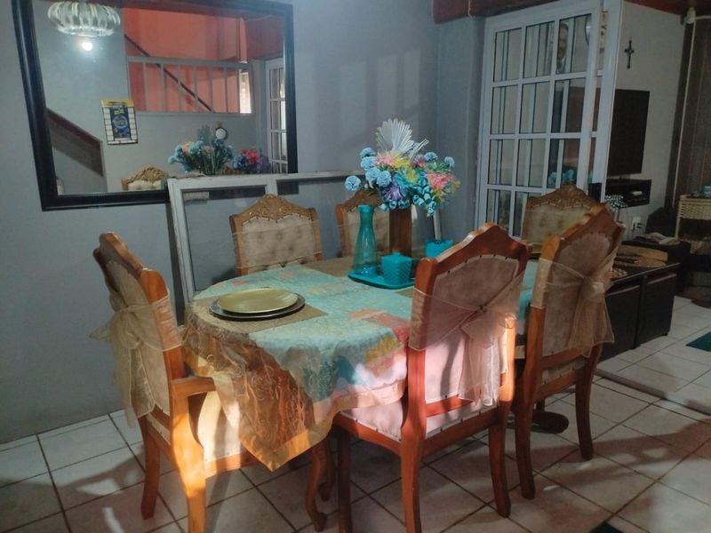 A dining area featuring tiled flooring, a large wall-mounted mirror, and glass-paneled french doors leading to an adjacent space.