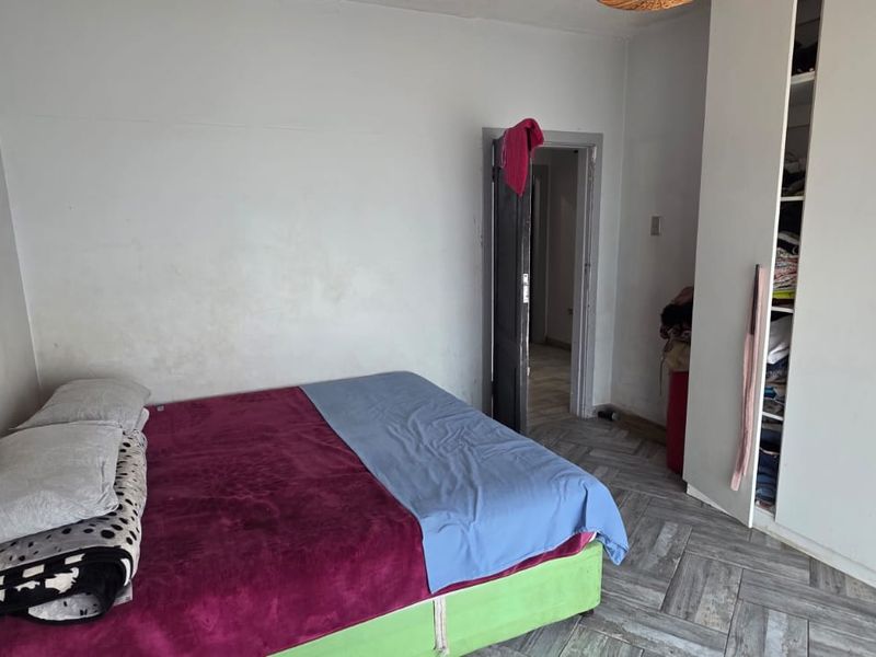 A bedroom featuring tiled flooring and a built-in wardrobe, requiring minor cosmetic updates to the wall finishes.
